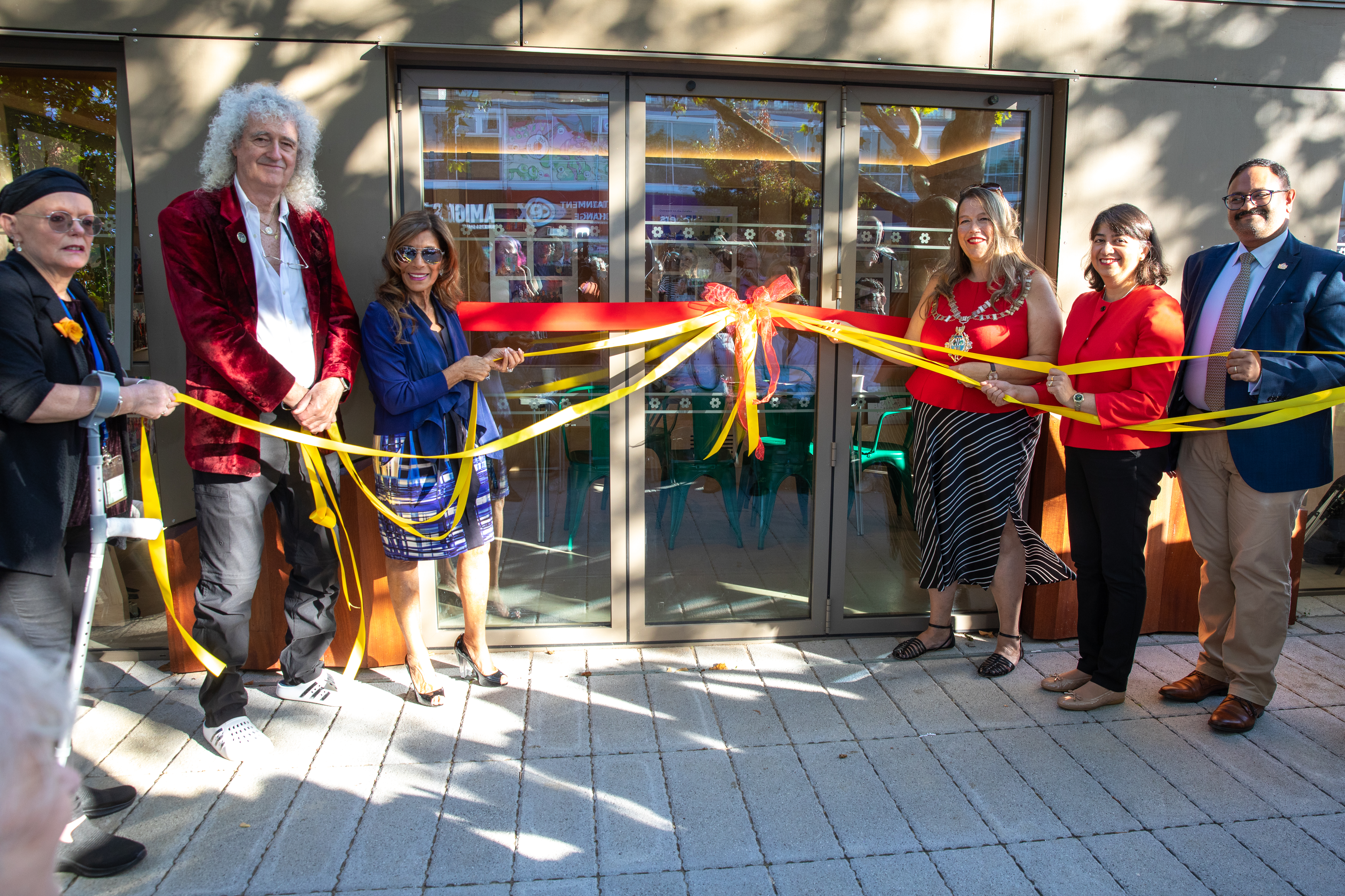 People holding ribbon tied to the doors of the Feltham Green Cabin