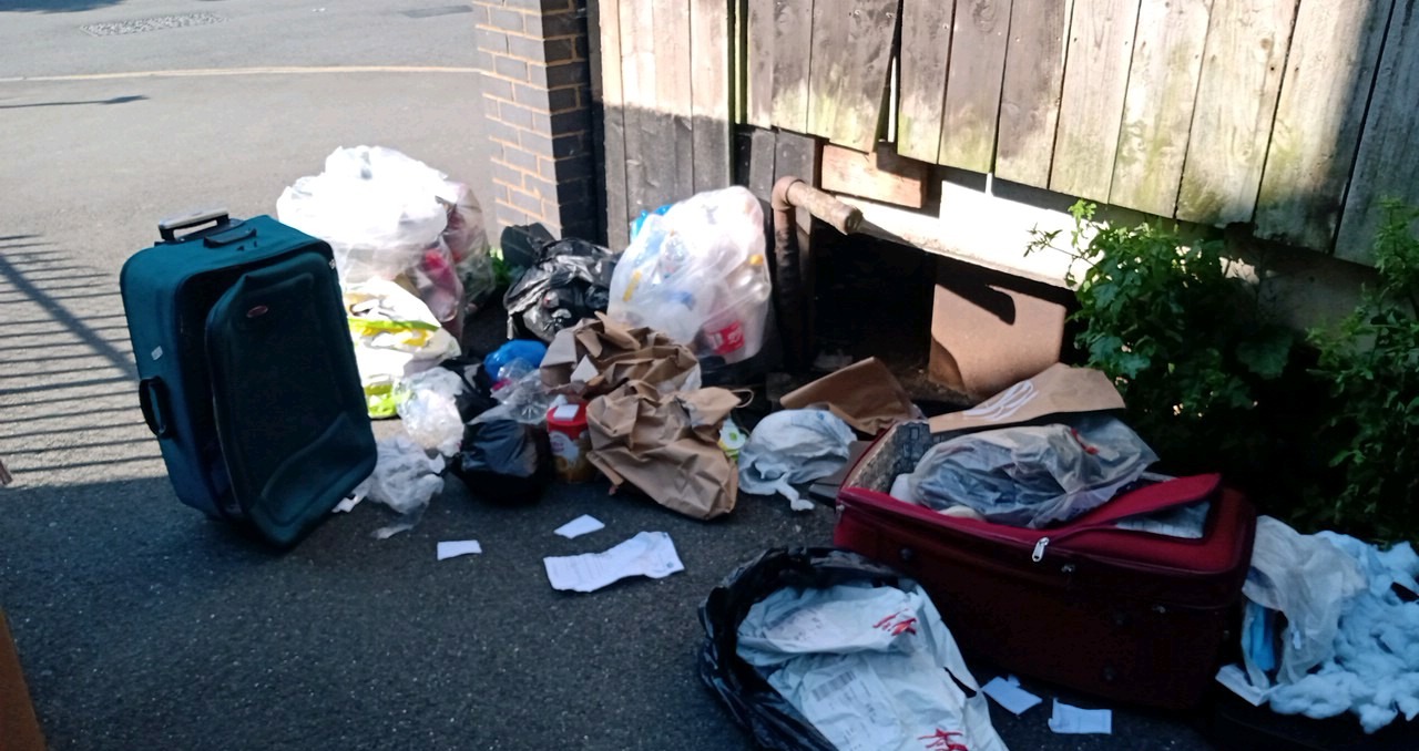 Fly Tipped rubbish both in and out of bags by a fance