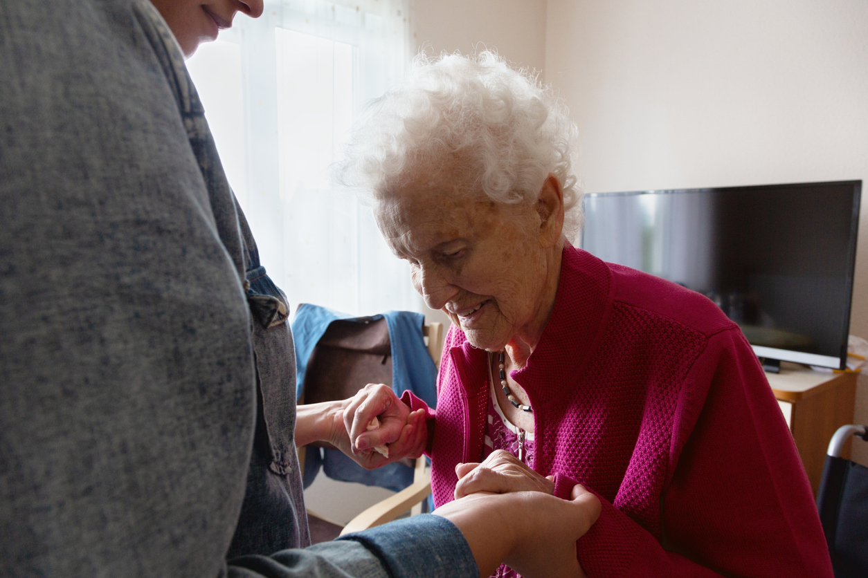 An elderly lady getting help to stand