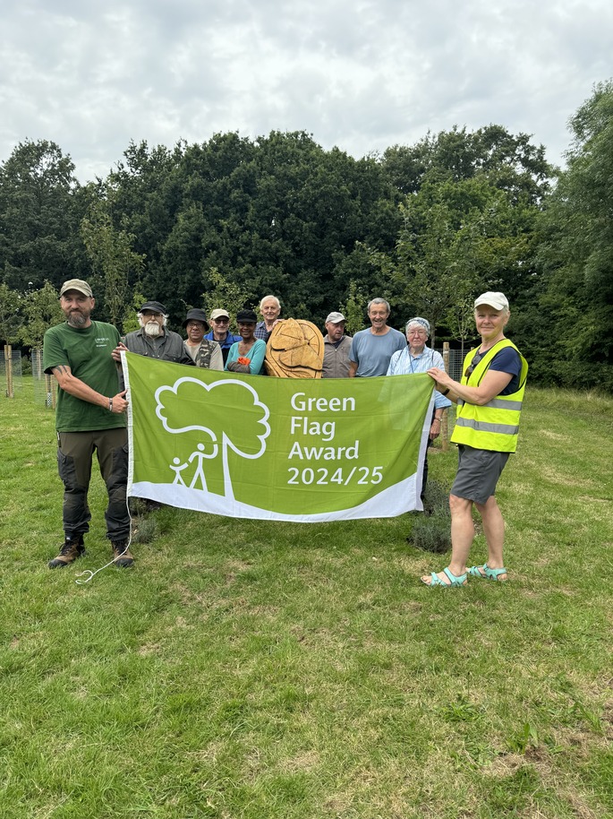 Volunteers at Pevensey Road Nature Reserve hold a banner commemorating their Green Flag Award in 2025