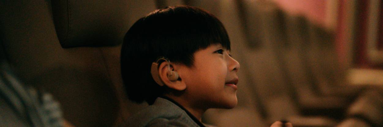Young person smiling while watching a film at the cinema.