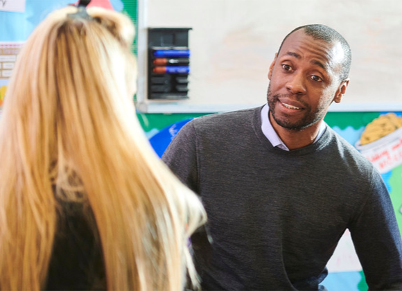 Parent talking to a teacher in an educational setting.