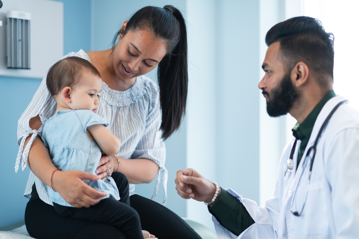 Mother and baby with doctor in clinical setting.