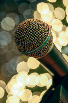 Close-up of a microphone with a blurred background of warm circular lights creating a bokeh effect.